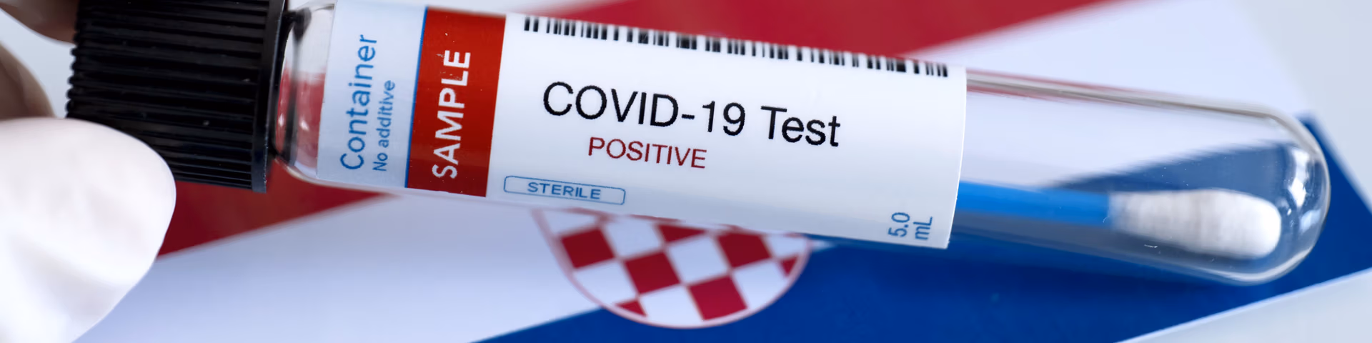 Testing for presence of coronavirus in Croatia. Tube containing a swab sample that has tested positive for COVID-19. Croatian flag in the background. covid test