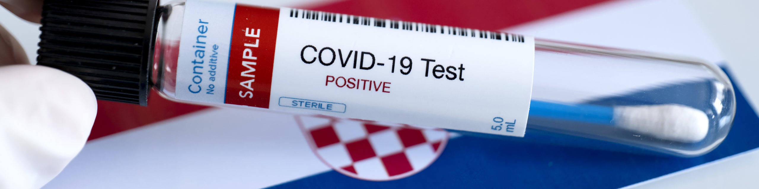 Testing for presence of coronavirus in Croatia. Tube containing a swab sample that has tested positive for COVID-19. Croatian flag in the background. covid test
