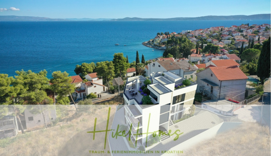 Luxus Meerblick 77m² Ensemble mit 2 Schlafzimmern, Terrasse und Südausrichtung - Eine moderne weiße Villa mit Dachterrassen bietet einen Blick auf das blaue Meer und ein kroatisches Küstendorf mit roten Dächern, Zypressen und einer Hügellandschaft. Der überlagerte Text lautet: "Hikel Homes-Traum- & Ferienimmobilien in Kroatien. (45215)