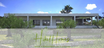 Modernes, einstöckiges Haus mit großen Fenstern und einer geräumigen Terrasse, umgeben von Olivenbäumen und Steinterrassen unter einem teilweise bewölkten blauen Himmel. Das "Heike Homes"-Logo und der deutsche Text überlagern den unteren Teil des Bildes. - 2 Meerblick Rohbau-Villen mit Haupt- und Gästehaus in absoluter privater Lage