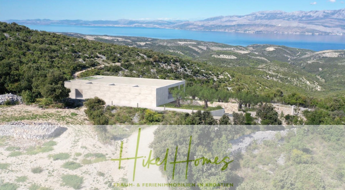 Ein modernes, rechteckiges Betonhaus steht auf einem grünen Hügel mit Blick auf das Meer und die fernen Berge unter einem blauen Himmel. Der Text "Hikel Homes - Traum- & Ferienimmobilien in Kroatien" erscheint am unteren Rand. - 2 Meerblick Rohbau-Villen mit Haupt- und Gästehaus in absoluter privater Lage