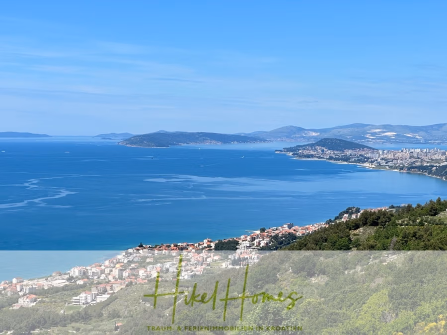 Exklusive 380m² Meerblick & Luxus in absoluter Alleinlage mit Privatspähre + Pool, Sommerküche, … - Eine malerische Ansicht einer Küstenstadt mit einer Ansammlung von Gebäuden in Ufernähe. Das klare, blaue Meer erstreckt sich bis zum Horizont. In der Ferne umgeben Hügel und Berge die Stadt unter einem strahlend blauen Himmel. (41904)