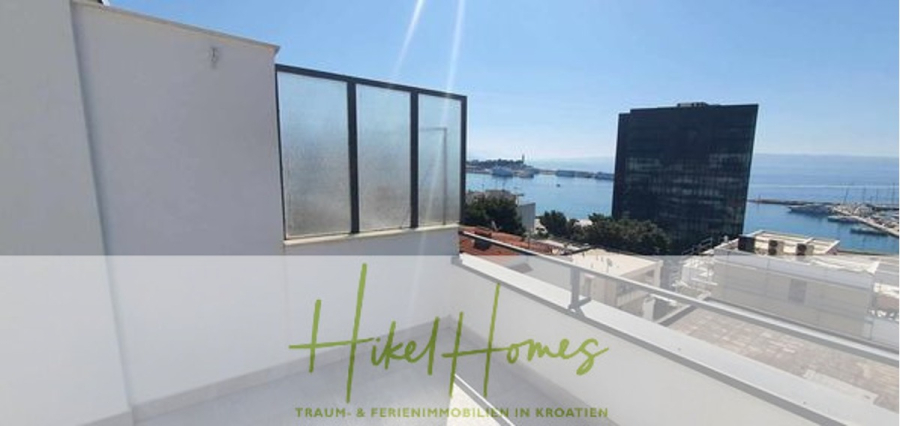 Charmantes 1-Zimmer-Appartement mit Meerblick im Herzen von Split mit Dachterrasse - Blick von einer hellen Dachterrasse mit weißen Wänden auf das Meer, entfernte Gebäude und einen klaren blauen Himmel. Der Text "Hikel Homes Traum- & Ferienimmobilien in Kroatien" ist am unteren Rand eingeblendet. (45420)