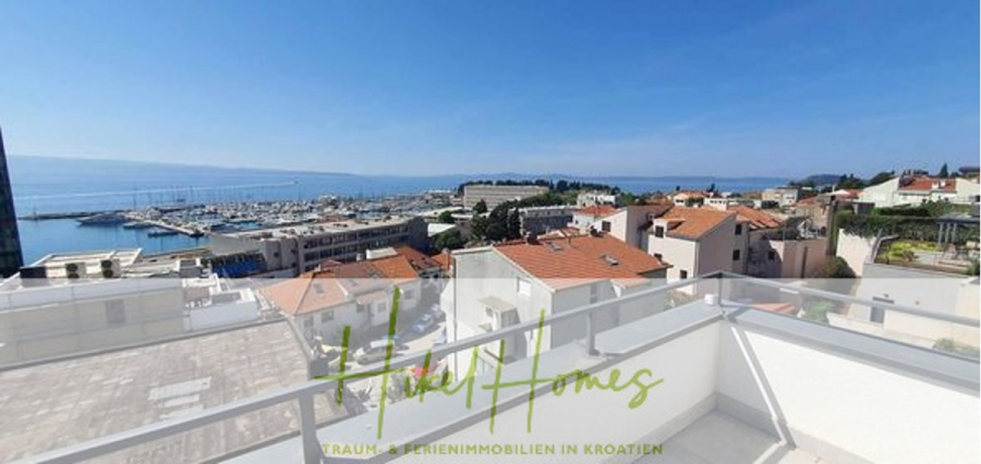 Charmantes 1-Zimmer-Appartement mit Meerblick im Herzen von Split mit Dachterrasse - Blick von einem Balkon auf einen Jachthafen mit Booten, weißgedeckten Häusern und dem Meer in der Ferne unter einem klaren blauen Himmel. Am unteren Rand des Bildes steht "Hitrev Homes". (45416)