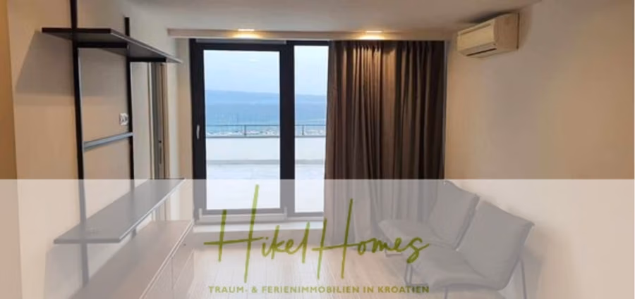 Charmantes 1-Zimmer-Appartement mit Meerblick im Herzen von Split mit Dachterrasse - Modernes, helles Zimmer mit wandmontiertem TV-Gerät, Klimaanlage und Glastür zum Balkon mit Meerblick. Der Balkon ist teilweise einsehbar. In der Ecke stehen zwei graue Stühle. Das Bild enthält den Text „Hikel Homes“ und eine Beschreibung auf Deutsch. (42221)