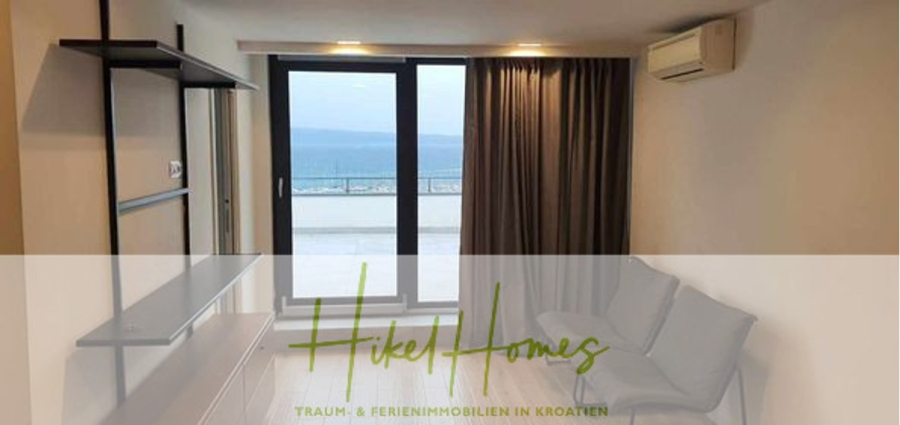 Charmantes 1-Zimmer-Appartement mit Meerblick im Herzen von Split mit Dachterrasse - Modernes Wohnzimmer mit grauem Sofa und TV-Ständer, große Glastüren, die auf einen Balkon mit Meerblick führen; der Text "Hikel Homes Traum- & Ferienimmobilien in Kroatien" erscheint quer über das Bild. (45407)