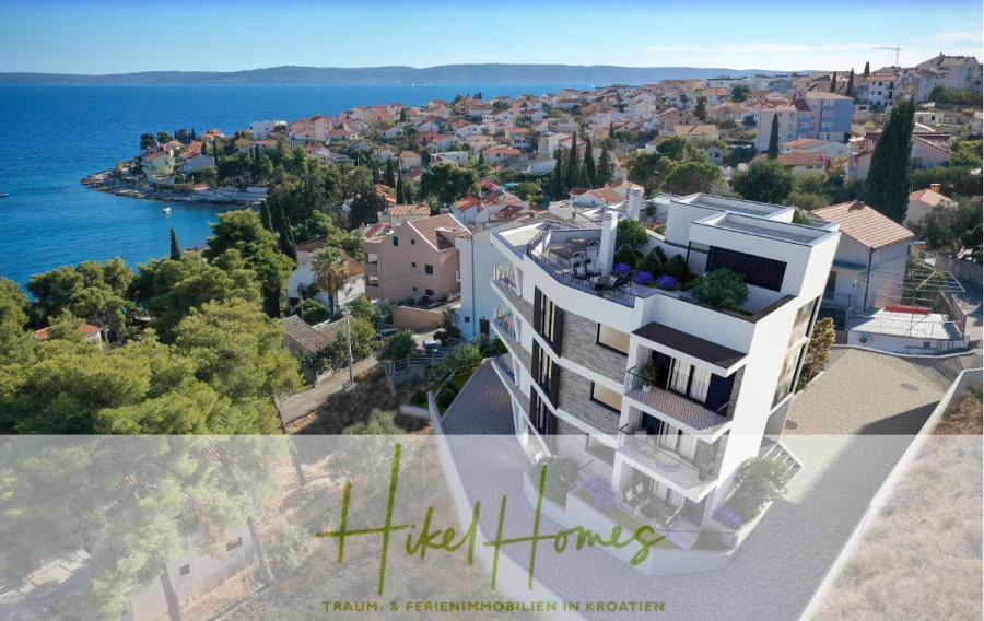 Luxus Meerblick 77m² Ensemble mit 2 Schlafzimmern, Terrasse und Südausrichtung – Einziehen 2025! - Ein modernes weißes Apartmentgebäude mit Blick auf die Adria in einer kroatischen Küstenstadt, umgeben von Bäumen und traditionellen Häusern. Unten steht „Hikel Homes Traum- & Ferienimmobilien in Kroatien“. (43791)