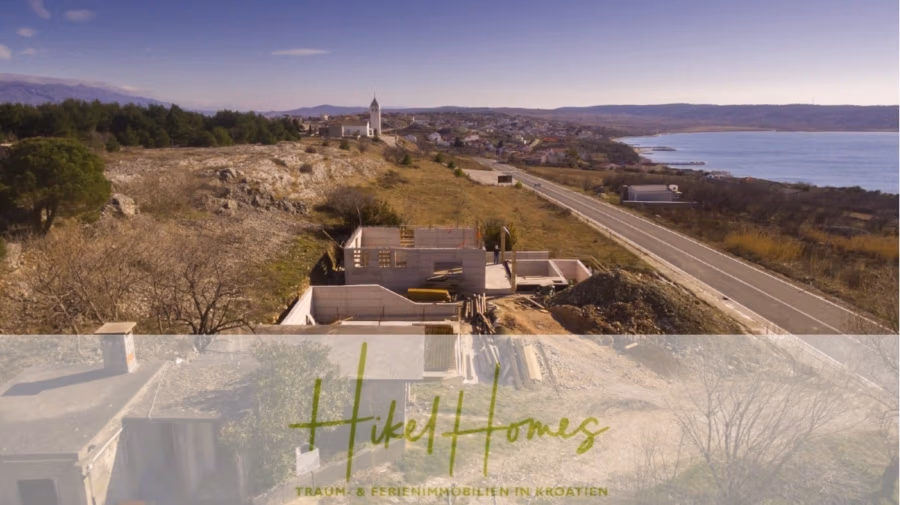 Neubau Meerblick 270m vom Meer entfernt – Hochwertigen Ausstattung – Fertigstellung Ende 2025 - Ein malerischer Blick auf die kroatische Küstenlandschaft mit einem halbfertigen Gebäude im Vordergrund. Eine Straße verläuft entlang der Küste und führt zu einem kleinen Dorf mit einer markanten Kirche. Der Text „Hikel Homes“ ist über das Bild gelegt. (42613)
