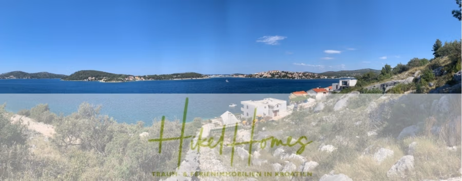 Luxus Villa Sunce / gegenüber Marina Frapa / Meerblick + direkter Meerzugang, Pool, mit 391m² WFL - Panoramablick auf eine Küstenlandschaft mit blauem Wasser, grünen Inseln und Häusern entlang der Küste. Im Vordergrund ist felsiges Gelände mit Büschen zu sehen. Der Himmel ist klar und blau. Die Textüberlagerung lautet „Hiedl Homes“ mit zusätzlichem Text in kleinerer Schrift. (42026)