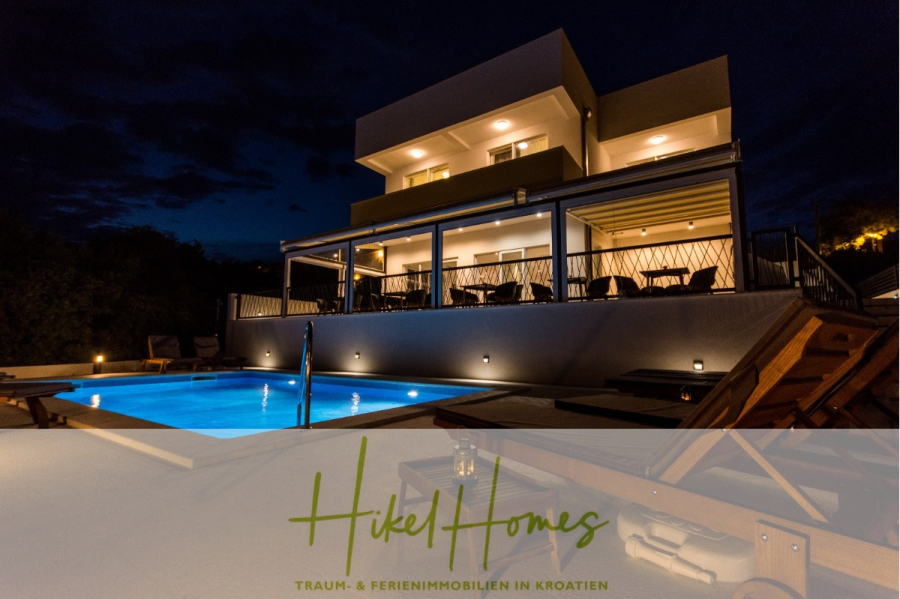 340m² Villa mit Pool auf der Insel Ciovo – vollständig möbiliert – auch Boutiquehotel möglich - Moderne Villa bei Nacht mit beleuchtetem Swimmingpool, Liegestühlen und einem Sitzbereich im Freien. Das Haus ist zweistöckig mit einem Balkon und warmer Beleuchtung. Textüberlagerung lautet "Hikel Homes, Traum- & Ferienimmobilien in Kroatien. (45556)