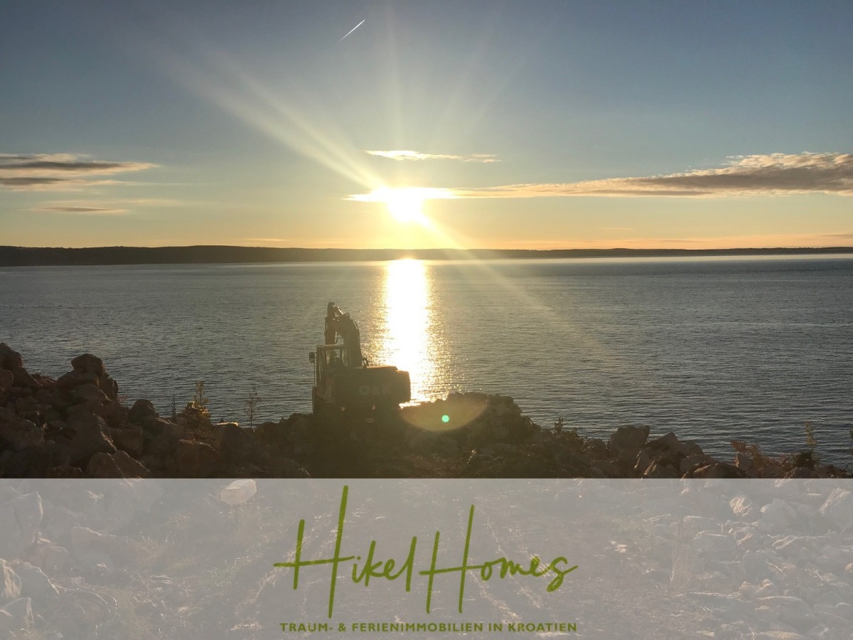 Bagger am felsigen Ufer bei Sonnenuntergang an einem ruhigen Gewässer, mit tief stehender Sonne am Horizont und Wolken am Himmel. Der Text "Hikel Homes: Traum- & Ferienimmobilien in Kroatien" erscheint am unteren Rand. - 1437m² in erste Reihe zum Meer / Bauland zur Bebauung mit 2 Villen – Planung ist vorhanden