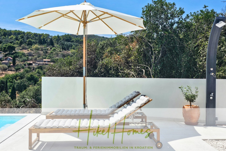 2 Meerblick Villen + freies Grundstück ideal zur Vermietungauf der Insel Dugi Otok jeweils mit Pool - Zwei gepolsterte Liegestühle stehen unter einem großen weißen Sonnenschirm neben dem Swimmingpool, mit einem bewaldeten Hügel im Hintergrund. Auf der rechten Seite befinden sich eine Außendusche und eine Topfpflanze. Der Text "Hike Homes" überlagert das Bild. (44753)