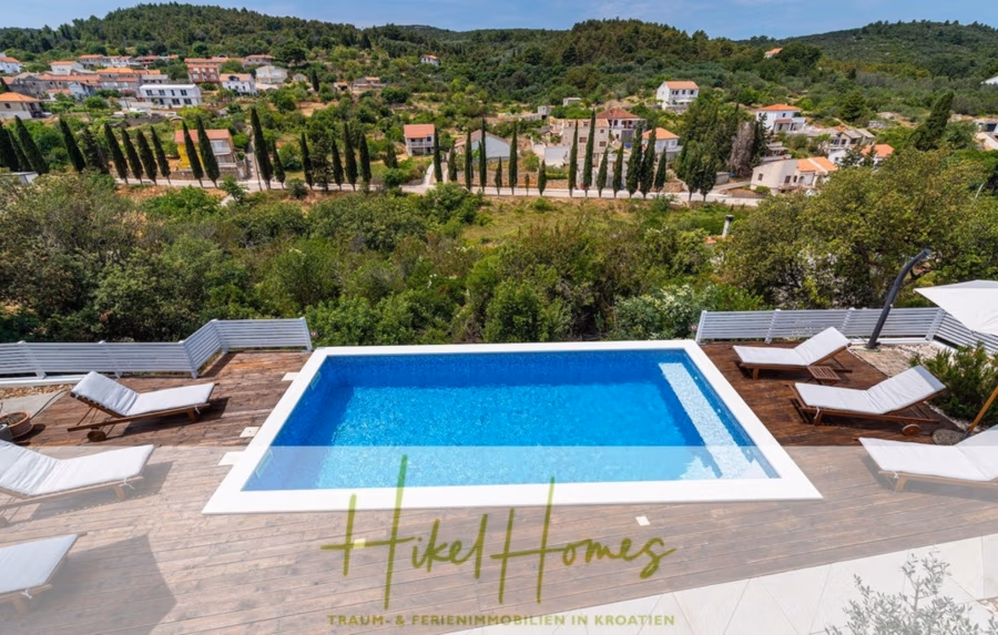 2 Meerblick Villen + freies Grundstück ideal zur Vermietungauf der Insel Dugi Otok jeweils mit Pool - Ein luxuriöser Außenpool, umgeben von weißen Sonnenliegen. Der Bereich ist von Grünflächen umgeben, mit einer kleinen Stadt und sanften Hügeln im Hintergrund. Der Poolbereich strahlt eine ruhige, urlaubsähnliche Atmosphäre aus. (42893)