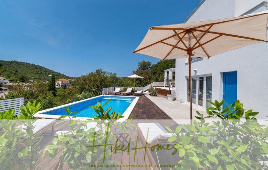 2 Meerblick Villen + freies Grundstück ideal zur Vermietungauf der Insel Dugi Otok jeweils mit Pool - Moderne weiße Villa mit Pool, Liegestühlen und großen Sonnenschirmen auf einer Holzterrasse, umgeben von Grün und Hügeln, unter einem klaren blauen Himmel. Die Textüberlagerung am unteren Rand lautet "Fiked Homes". (44736)