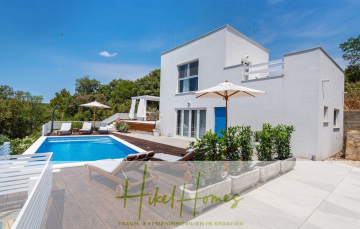 Moderne weiße Villa mit privatem Pool, Liegestühlen und Sonnenschirmen im Freien, umgeben von Grün, unter einem klaren blauen Himmel. Logo und Text am unteren Rand lauten "Hikel Homes Traum- & Ferienimmobilien in Kroatien.". - 2 Meerblick Villen + freies Grundstück ideal zur Vermietungauf der Insel Dugi Otok jeweils mit Pool