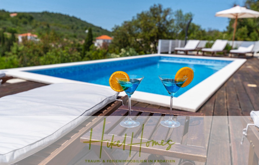 2 Meerblick Villen + freies Grundstück ideal zur Vermietungauf der Insel Dugi Otok jeweils mit Pool - Zwei blaue Cocktails mit Orangenscheiben sitzen auf einem Holztisch am Pool, umgeben von weißen Liegestühlen und grünen Bäumen unter einem sonnigen Himmel. Der Text "Hike Homes" erscheint am unteren Rand. (44735)