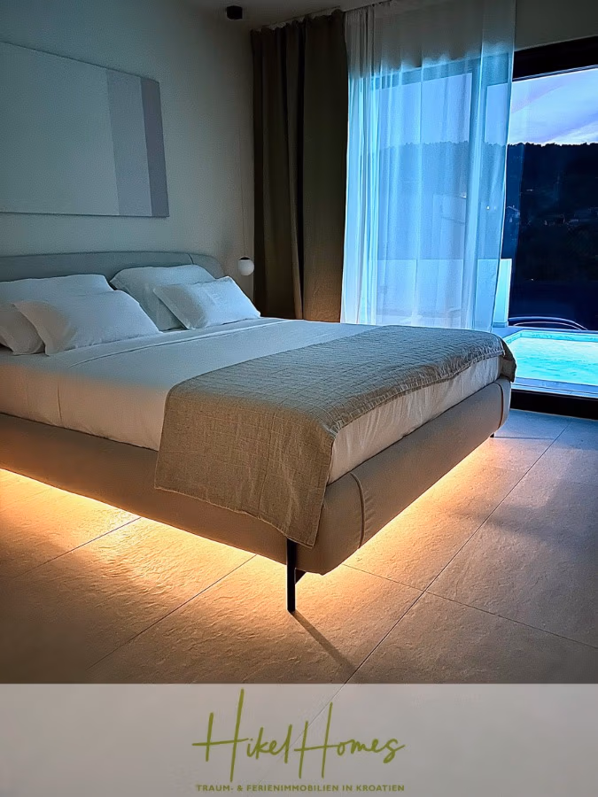 2 Meerblick Villen + freies Grundstück ideal zur Vermietungauf der Insel Dugi Otok jeweils mit Pool - Modernes Schlafzimmer mit einem von unten beleuchteten Schwebebett und weißer und grauer Bettwäsche. Ein großes Fenster mit transparenten Vorhängen bietet Blick auf Pool und Hügel. Das Zimmer strahlt eine ruhige und luxuriöse Atmosphäre aus. (42911)