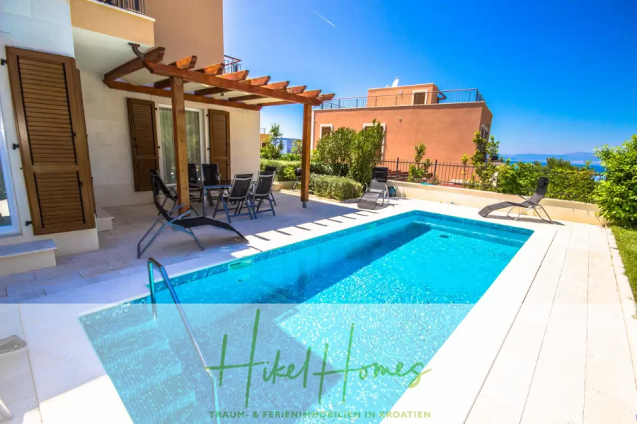 Villa im Mittelmeerstil mit 3 SZ, Pool, Dachterrasse mit Meerblick (7) - Moderner Villeninnenhof mit Swimmingpool, Sonnenliegen und Essbereich im Freien unter einer Holzpergola. Ein strahlend blauer Himmel und eine mediterrane Landschaftsgestaltung umgeben die Szene. Logo "Hikel Homes" am unteren Rand. (44828)
