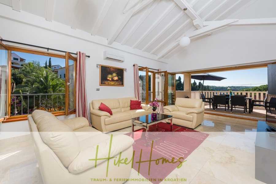 Villa mit 3 großzügigen Appartements mit jeweils 3 SZ, Küche, 2 x Pool, … - Helles, modernes Wohnzimmer mit cremefarbenen Sofas, roten Akzenten, gläsernem Couchtisch und großen Fenstern, die sich zu einem Balkon mit Sitzgelegenheiten im Freien und einer malerischen Aussicht öffnen. Weiße Gewölbedecken und Marmorböden verstärken das luftige Gefühl. (46278)