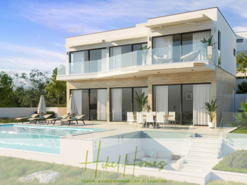 Moderne zweistöckige Villa mit großen Glasfenstern, einem geräumigen Balkon, Liegestühlen und Sonnenschirmen an einem Außenpool. Das Haus ist von viel Grün umgeben, und der Himmel ist klar. Der Text am unteren Rand lautet "Hikel Homes". - Villa Anastasia (1.Reihe) – Neubauvilla – direkt am Strand in wunderbarer Bucht