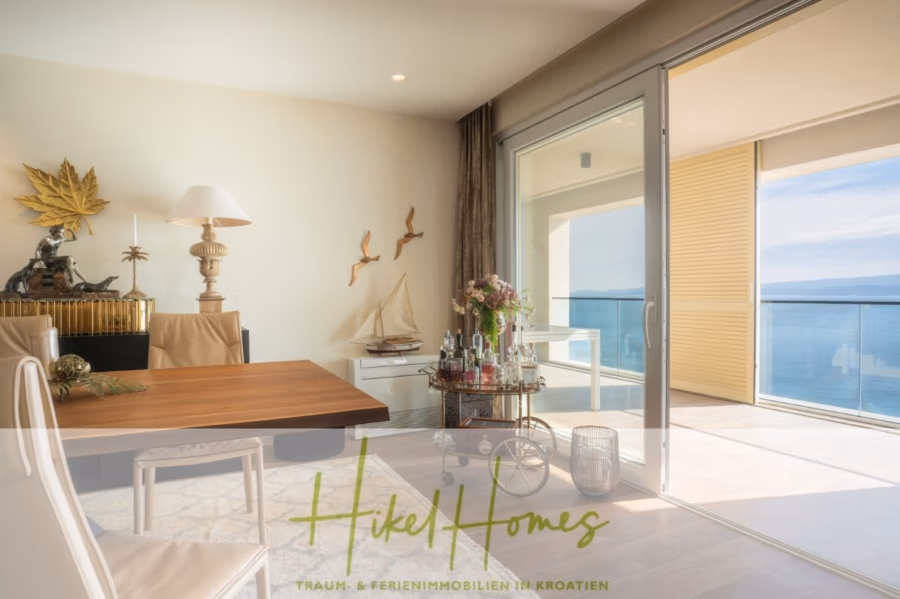 MEERBLICK & KUNST Designer Luxus Appartement mit 3 Schlafzimmer – großer Loggia - Modernes Apartment-Interieur mit Esstisch, Stühlen und Dekoartikeln auf einem Sideboard aus Holz. Eine große Glasschiebetür öffnet sich zu einem Balkon mit Meerblick. Sonnenlicht erhellt den Raum und unterstreicht das elegante und minimalistische Dekor. (41083)