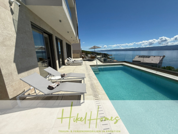 Moderne Poolterrasse mit zwei Liegestühlen, Sonnenschirm und atemberaubendem Meerblick unter strahlend blauem Himmel. Die Szene ist hell und heiter, mit Küstengebäuden im Hintergrund. - Erstbezug – ab sofort und Herbst genießen! Schlüsselfertige Meerblick Villa, 3SZ, Pool, …