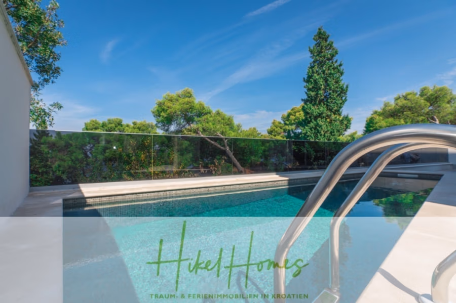 Erstbezug-Neubau Villa / Luxus Ausstattung / Pool / … - Ein Swimmingpool mit Metallgeländer an einem sonnigen Tag. Umliegende Bäume und Sträucher sind vor einem strahlend blauen Himmel sichtbar. Der Text unten lautet: „Hikel Homes – Traum- & Ferienimmobilien in Kroatien.“. (42538)