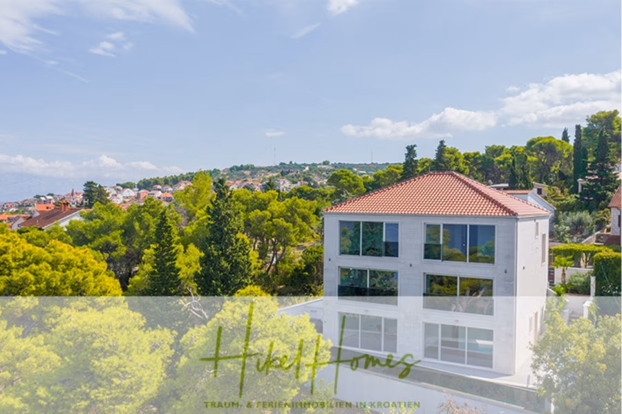 Erstbezug-Neubau Villa / Luxus Ausstattung / Pool / … - Modernes weißes Haus mit rotem Ziegeldach, umgeben von grünen Bäumen, unter klarem blauen Himmel. Im Hintergrund ist eine Stadt mit bunten Dächern zu sehen. Die Textüberlagerung am unteren Rand lautet „Hikel Homes“ und „Traum- & Ferienimmobilien in Kroatien“. (42536)