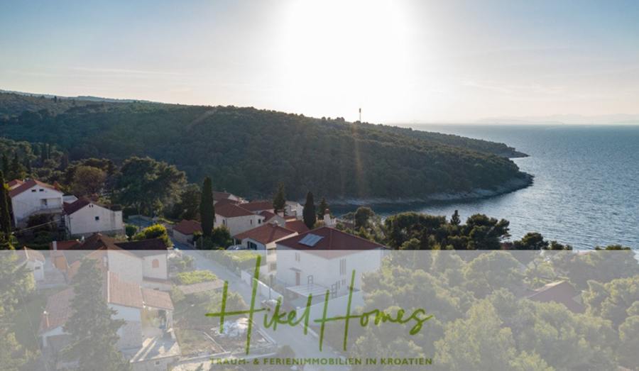 Erstbezug-Neubau Villa / Luxus Ausstattung / Pool / … - Ein kroatisches Küstendorf mit roten Häusern, umgeben von grünen Bäumen, vor dem Hintergrund eines Hügels und des blauen Meeres unter einem strahlenden Himmel. Im Vordergrund ist ein halbtransparentes Logo mit der Aufschrift "Hikel Homes" zu sehen. (45922)
