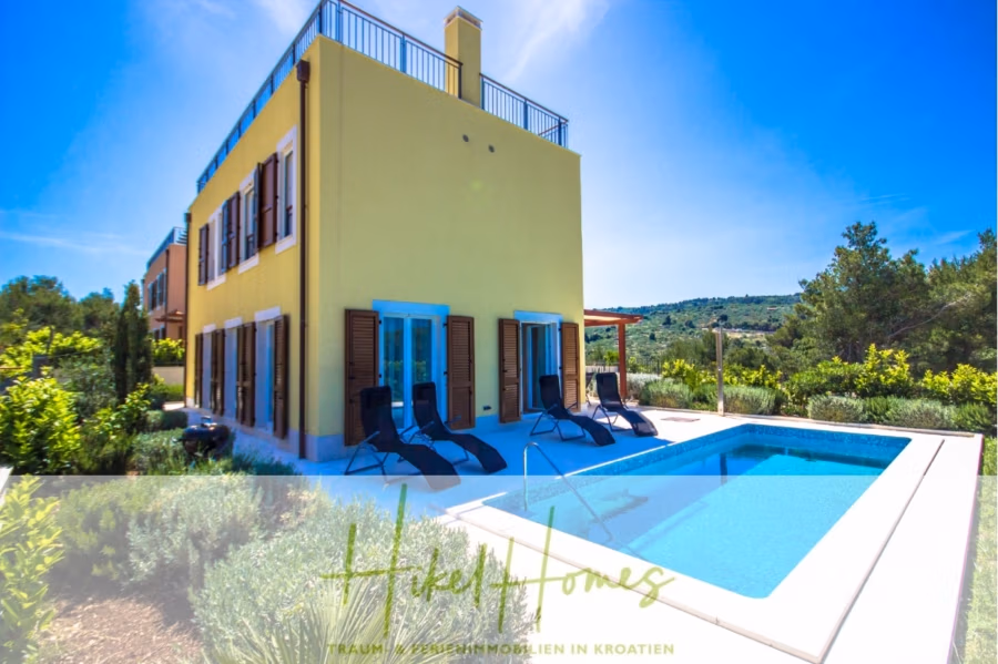 Villa im Mittelmeerstil mit 3 SZ, Pool, Dachterrasse mit Meerblick (2) - Ein leuchtend gelbes zweistöckiges Haus mit Holzläden, umgeben von üppigem Grün. Im Vordergrund ein rechteckiger Swimmingpool mit Liegestühlen. Der Himmel ist klar und blau. Unten steht „Hikel Homes“. (42189)