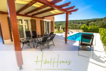 Eine sonnenbeschienene Terrasse mit Sitzgelegenheiten im Freien und einer hölzernen Pergola blickt auf einen privaten Pool. Im Hintergrund sind grüne Hügel zu sehen. Das Bild enthält das "Hikel Homes"-Logo und einen Text über Ferienimmobilien in Kroatien. - Villa im Mittelmeerstil mit 3 SZ, Pool, Dachterrasse mit Meerblick (1)