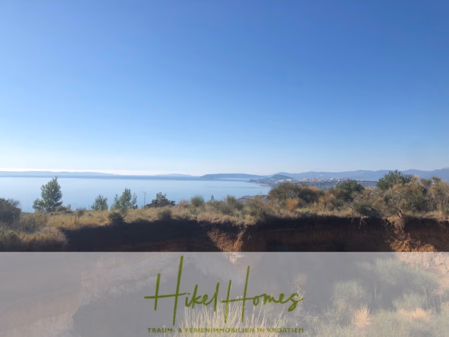 Absolute Alleinlage mit Blick auf Meer, Insel Brac und Split – 511m² auf über 3100m² Grundstück - Küstenlandschaft mit klarem, blauem Himmel und ruhiger See. In der Ferne zeichnet sich eine Küstenlinie mit Bäumen und niedrigen Hügeln ab, die eine ruhige und malerische Szenerie schaffen. Das Bild zeigt unten das Logo von „Hikel Homes“. (43245)