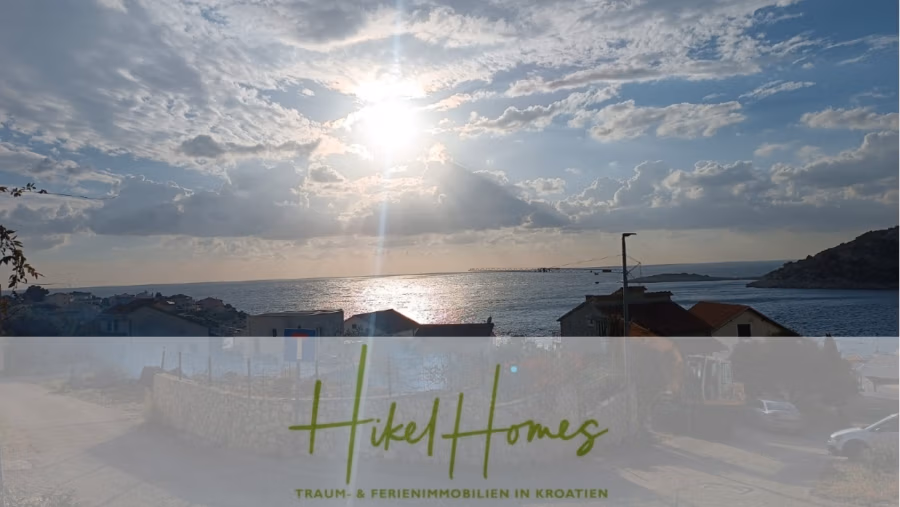 Einziehen im Sommer – Meerblick Neubau-Luxusvilla mit Einrichtung, Infinitypool & Raumkonzept - Ein malerischer Blick auf eine kroatische Küstenregion mit Sonnenuntergang über dem Meer und leicht bewölktem Himmel. Häuser säumen die Küste, im Hintergrund sind Hügel zu sehen. Ein halbtransparentes Banner am unteren Rand trägt die Aufschrift „Hikel Homes – Traum- & Ferienimmobilien in Kroatien“. (43094)