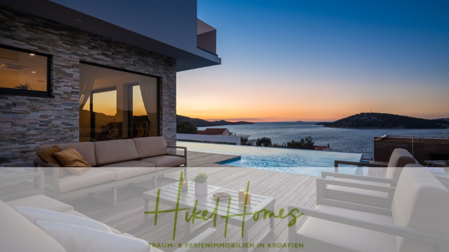 Bezugsfertige Luxus-Meerblick Villa mit 4 SZ, Pool, Sauna, Fitness, Jacuzzi, vollständig möbliert - Moderne Terrasse mit beigen Außensofas und einem Pool mit Blick auf das Meer bei Sonnenuntergang; im Hintergrund sind die Küstenhügel zu sehen. Der Text "Hikel Homes" erscheint am unteren Rand des Bildes. (45654)
