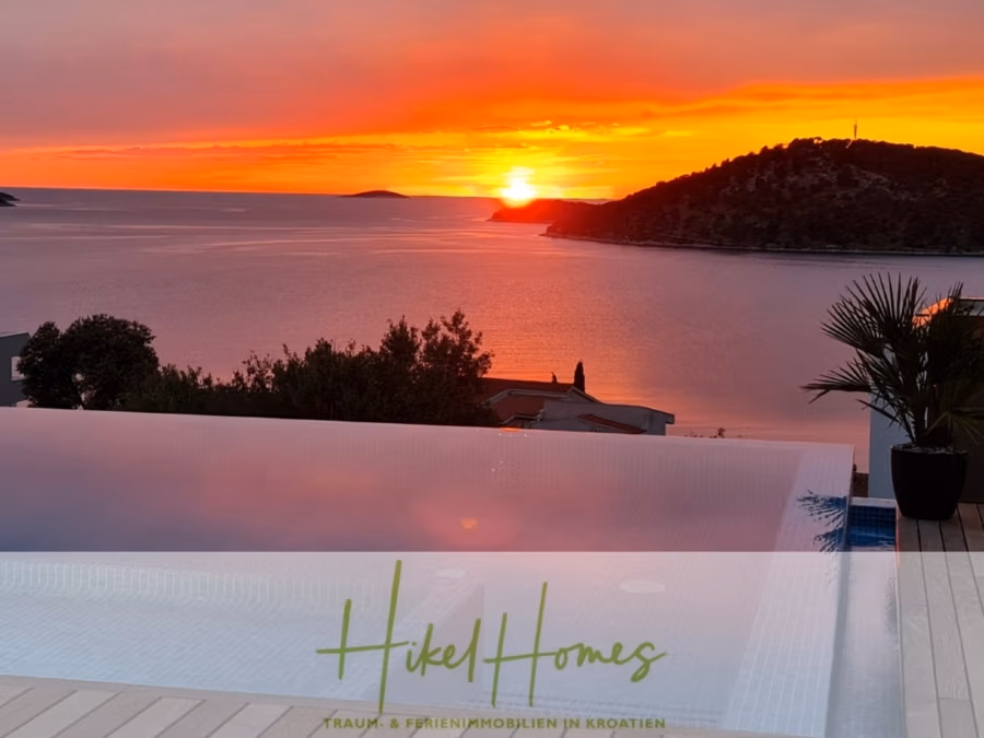 Bezugsfertige Luxus-Meerblick Villa mit 4 SZ, Pool, Sauna, Fitness, Jacuzzi, vollständig möbliert - Ein atemberaubender Sonnenuntergang über dem ruhigen Meer, die Sonne teilweise hinter einem fernen Hügel verborgen. Im Vordergrund spiegelt sich der Infinity-Pool im farbenfrohen Himmel. Das Bild enthält den Text: „Hikel Homes – Traum- & Ferienimmobilien in Kroatien.“. (42254)