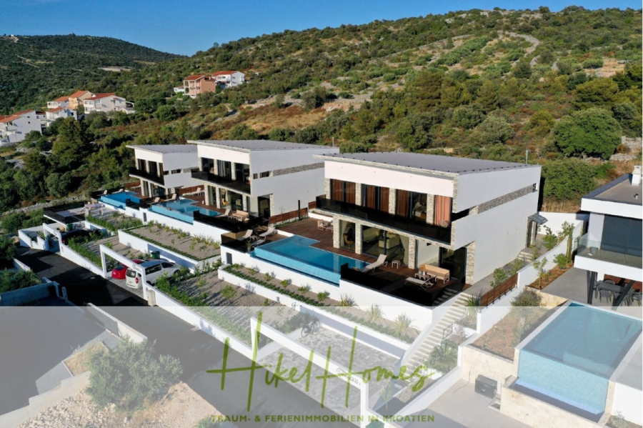 Bezugsfertige Luxus-Meerblick Villa mit 4 SZ, Pool, Sauna, Fitness, Jacuzzi, vollständig möbliert - Luftaufnahme von modernen weißen Villen mit privaten Pools an einem Hang, umgeben von Grün und anderen Häusern in Kroatien. Das Logo "Hike Homes" und ein Slogan sind am unteren Rand des Bildes eingeblendet. (45632)