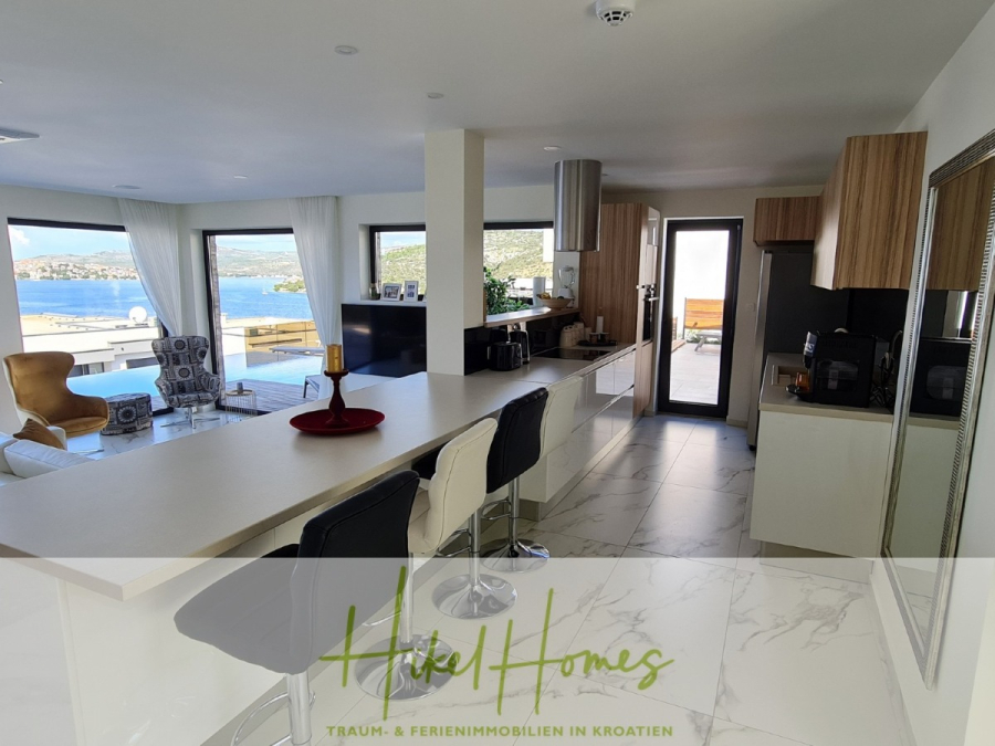 Bezugsfertige Luxus-Meerblick Villa mit 4 SZ, Pool, Sauna, Fitness, Jacuzzi, vollständig möbliert - Moderne offene Küche und Wohnbereich mit großen Fenstern mit Blick auf das Meer, weißen Arbeitsflächen, Holzschränken und modernen Möbeln. Heller, luftiger Raum mit natürlichem Licht und malerischem Wasserblick. (45631)