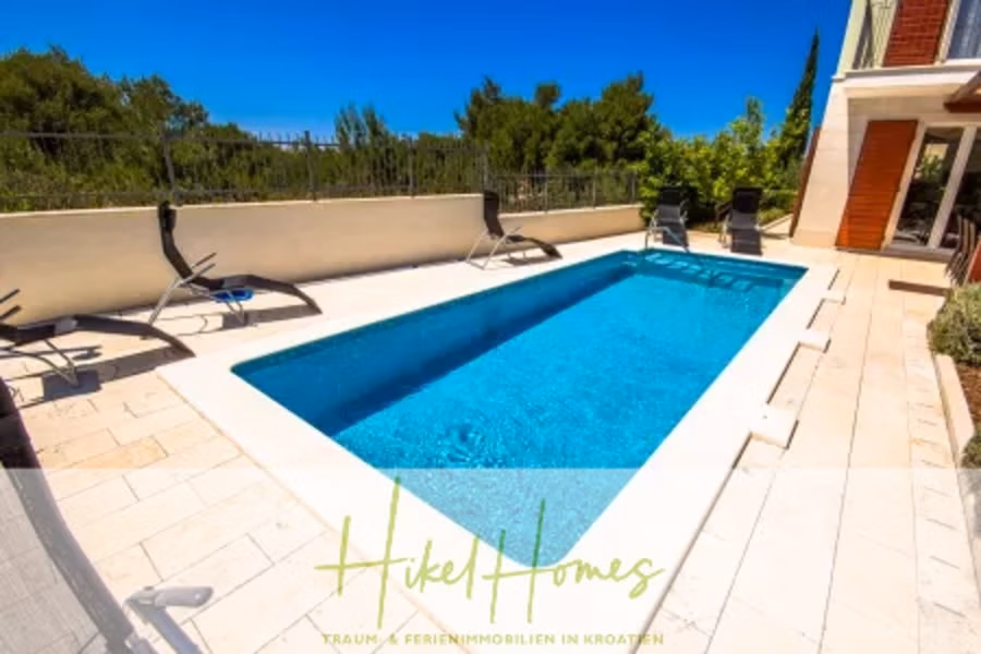 Villa im Mittelmeerstil mit 3 SZ, Pool, Dachterrasse mit Meerblick – möbiliert (15) - Rechteckiger Außenpool mit türkisfarbenem Wasser, umgeben von einer sonnigen Terrasse mit Liegestühlen. Im Hintergrund üppiges Grün. Rechts ist ein Haus mit großen Fenstern zu sehen. Unten ist ein Schild mit der Aufschrift „Hikel Homes“ mit zusätzlichem Text zu sehen. (42332)