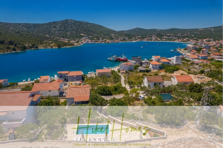 Meerblick Appartementhaus mit 3 Wohnungen, Karten, Terrassen - Malerische Aussicht auf ein Küstendorf mit rot gedeckten Häusern an einer blauen Bucht, umgeben von grünen Hügeln. Mehrere Boote liegen im Wasser vor Anker. Unten ist das Logo von „HikeHomes Traum & Ferienimmobilien in Kroatien“ zu sehen. (40979)