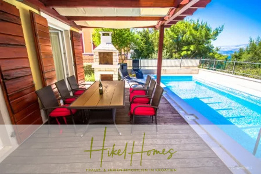 Villa im Mittelmeerstil mit 3 SZ, Pool, Dachterrasse mit Meerblick – möbiliert (9) - Eine moderne Terrasse mit einem Esstisch aus Holz und Stühlen mit roten Kissen, neben einem blauen Pool und einem Steingrill, alles im Schatten einer Pergola aus Holz. Eine üppige Bepflanzung umgibt den Bereich. (45719)