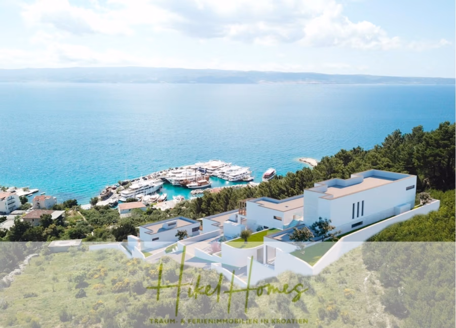 Villa Dalia – von jedem Zimmer aus Meerblick mit 4 Schlafzimmer / 4 Bädern / Loggia / Pool / … - Luftaufnahme einer modernen, weißen Villa mit Blick auf einen Yachthafen voller Boote auf dem klaren, blauen Meer. Üppiges Grün umgibt das Anwesen, und unter einem teilweise bewölkten Himmel sind sanfte Hügel zu sehen. (41357)