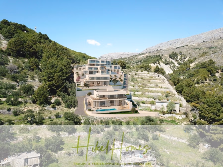 Villa Dalia – von jedem Zimmer aus Meerblick mit 4 Schlafzimmer / 4 Bädern / Loggia / Pool / … - Ein modernes Resort am Hang mit mehreren Reihenhäusern, umgeben von Grün. Die Gebäude haben Flachdächer und große Fenster. Bergiges Gelände und strahlend blauer Himmel bilden eine malerische Kulisse. (41356)