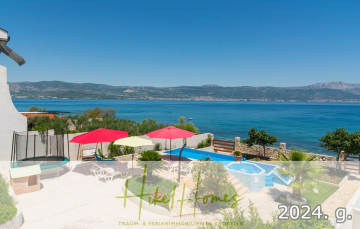 Eine sonnige Terrasse am Meer mit bunten Sonnenschirmen, Liegestühlen und einem kleinen Pool bietet einen Blick auf das ruhige blaue Meer und die fernen Berge. Grünflächen und Steinmauern umgeben den Bereich und schaffen eine entspannte Urlaubsatmosphäre. - 1. Reihe dirkt Meer mit 5 SZ, Pool, Jacuzzi, … auf der Insel Ciovo (bei Trogir mit 2 Brücken)