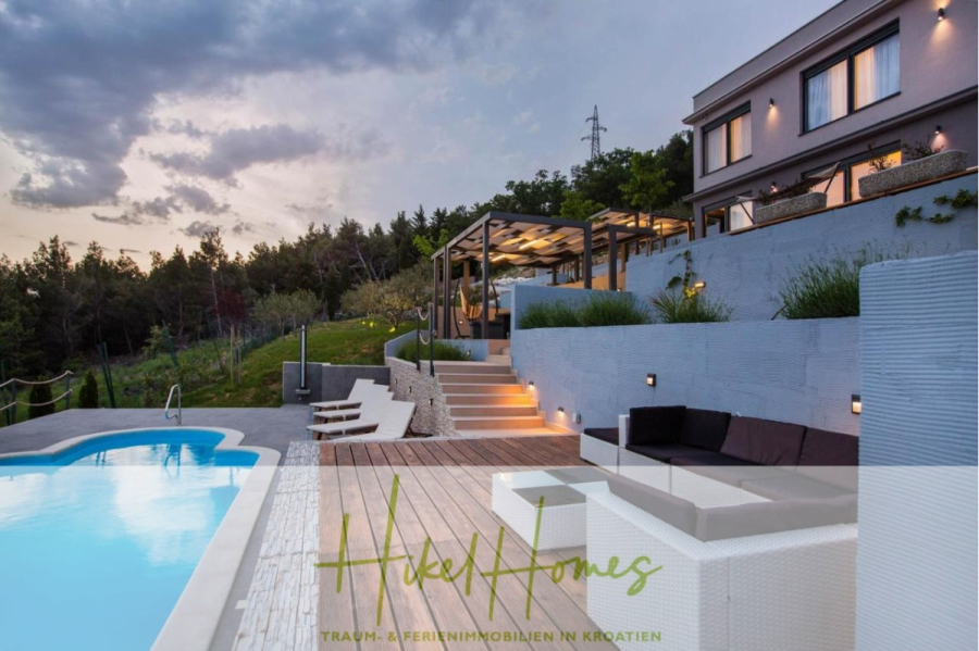 Meerblick auf 2903m² großem Grundstück in wunderbarer Alleinlage am Stadtrand von Split - Eine moderne Villa in Hanglage mit Swimmingpool, Sitzgelegenheiten im Freien und Terrasse, umgeben von Grün in der Abenddämmerung. Der Text "Hide Homes Traum- & Ferienimmobilien in Kroatien" ist eingeblendet. (45869)