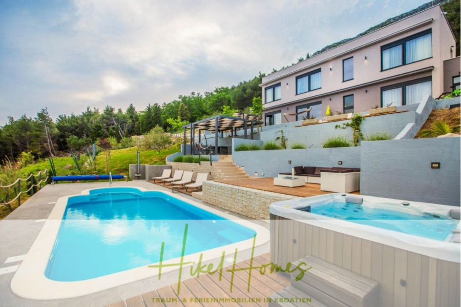 Meerblick auf 2903m² großem Grundstück in wunderbarer Alleinlage am Stadtrand von Split - Moderne Villa mit großen Fenstern, Außenpool, Whirlpool, Liegestühlen und einer Terrasse, umgeben von Grün und Hügeln. Die Umgebung ist luxuriös und ruhig, ideal zum Entspannen. Das Logo "Hike Homes" erscheint am unteren Rand. (45858)