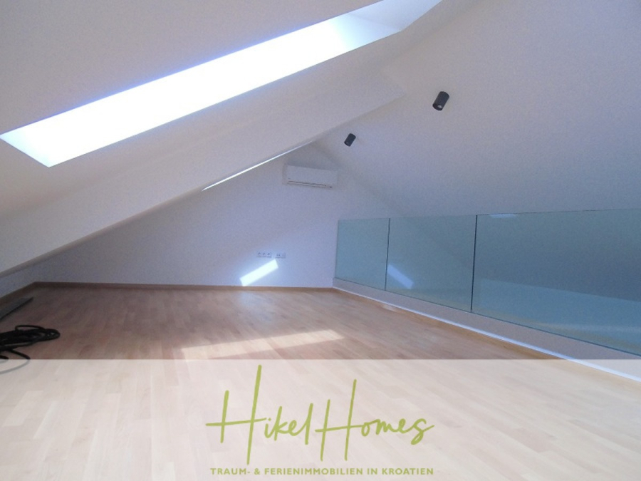 Galerie Wohnung, 3 Schlafzimmer / 70m zum Meer / Pool / 2 Bäder - Ein modernes Loftzimmer mit schrägen Decken, hellem Holzfußboden, einem großen Dachfenster, einer an der Wand montierten Klimaanlage, einem Glasgeländer und weißen Wänden. Der Raum wirkt hell und minimalistisch. (46582)