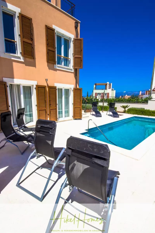 Villa im Mittelmeerstil mit 3 SZ, Pool, Dachterrasse mit Meerblick (3/4) - Ein kleiner Swimmingpool im Freien, umgeben von Liegestühlen und einem beigen Gebäude mit hölzernen Fensterläden, unter einem klaren blauen Himmel. (45750)