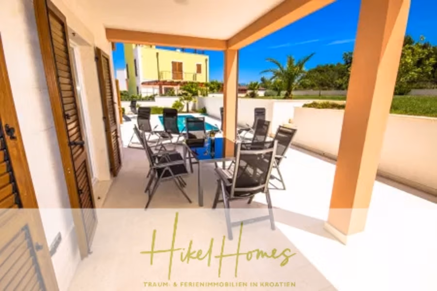 Villa im Mittelmeerstil mit 3 SZ, Pool, Dachterrasse mit Meerblick (3/4) - Überdachte Terrasse mit Tisch und Stühlen mit Blick auf einen Swimmingpool. Im Hintergrund sind Palmen und moderne Gebäude zu sehen. Unten ist der Text „Hikel Homes“ mit einem Slogan eingeblendet. (43306)