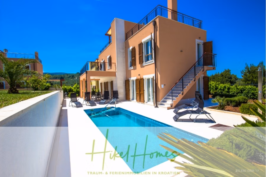 Villa im Mittelmeerstil mit 3 SZ, Pool, Dachterrasse mit Meerblick (3/4) - Moderne zweistöckige Villa mit Pool, umgeben von Liegestühlen und üppigem Grün. Das Haus verfügt über beigefarbene Wände, Holzfensterläden und eine Dachterrasse. Der Himmel ist klar und blau, und im Hintergrund ist ein Berg zu sehen. (43298)