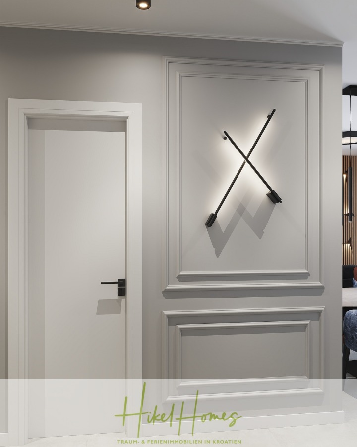 Meerblick 60m² Neubauwohnung mit 2 Schlafzimmer, Balkon und Südausrichtung - Ein moderner, minimalistischer Flur mit einer weißen Tür, grau getäfelten Wänden und einer schwarzen, X-förmigen Wandleuchte. Der Boden ist hell, und am unteren Rand des Bildes ist das Logo von Hiked Homes zu sehen. (45289)